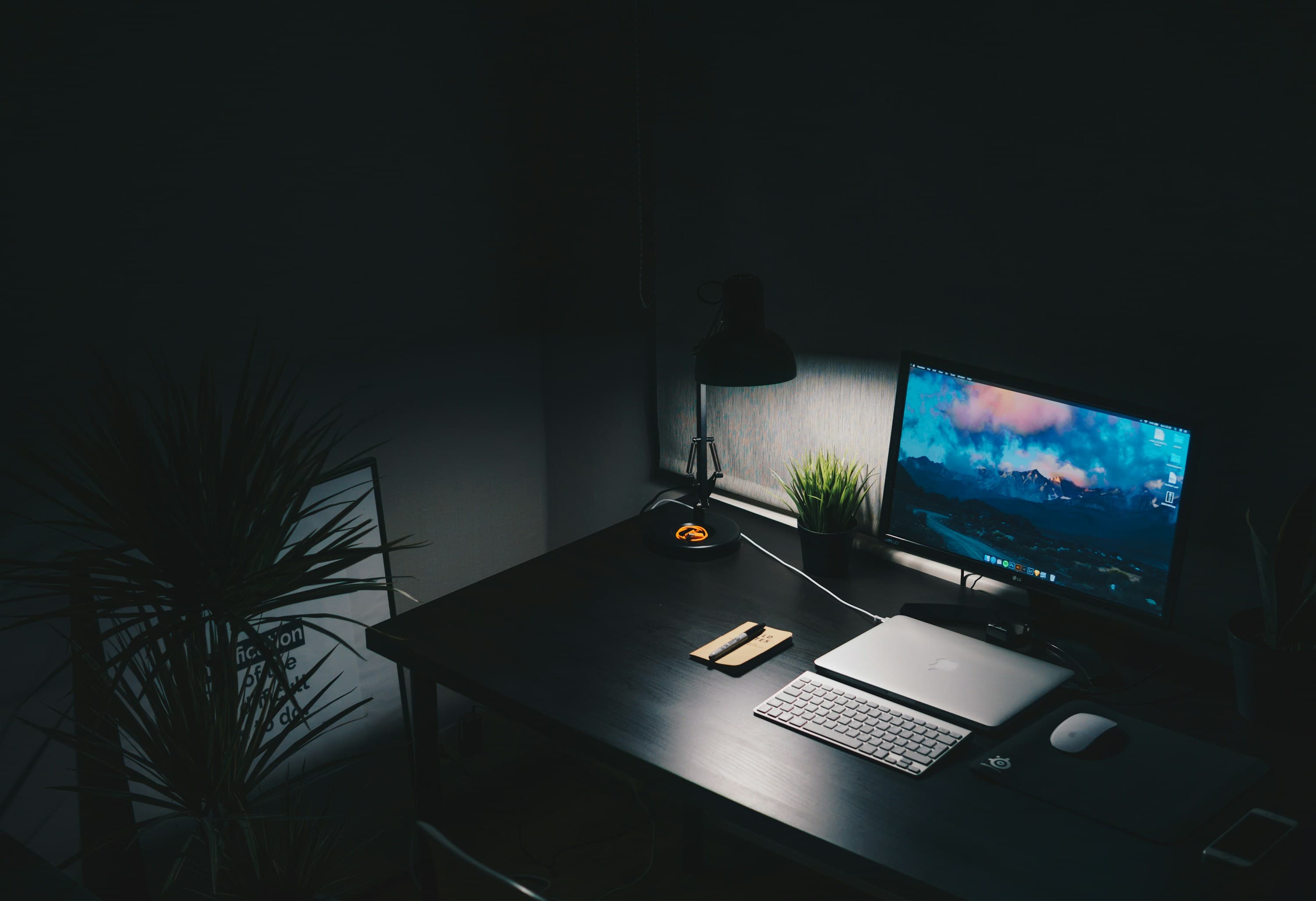 A Mac desk setup photographed in low light