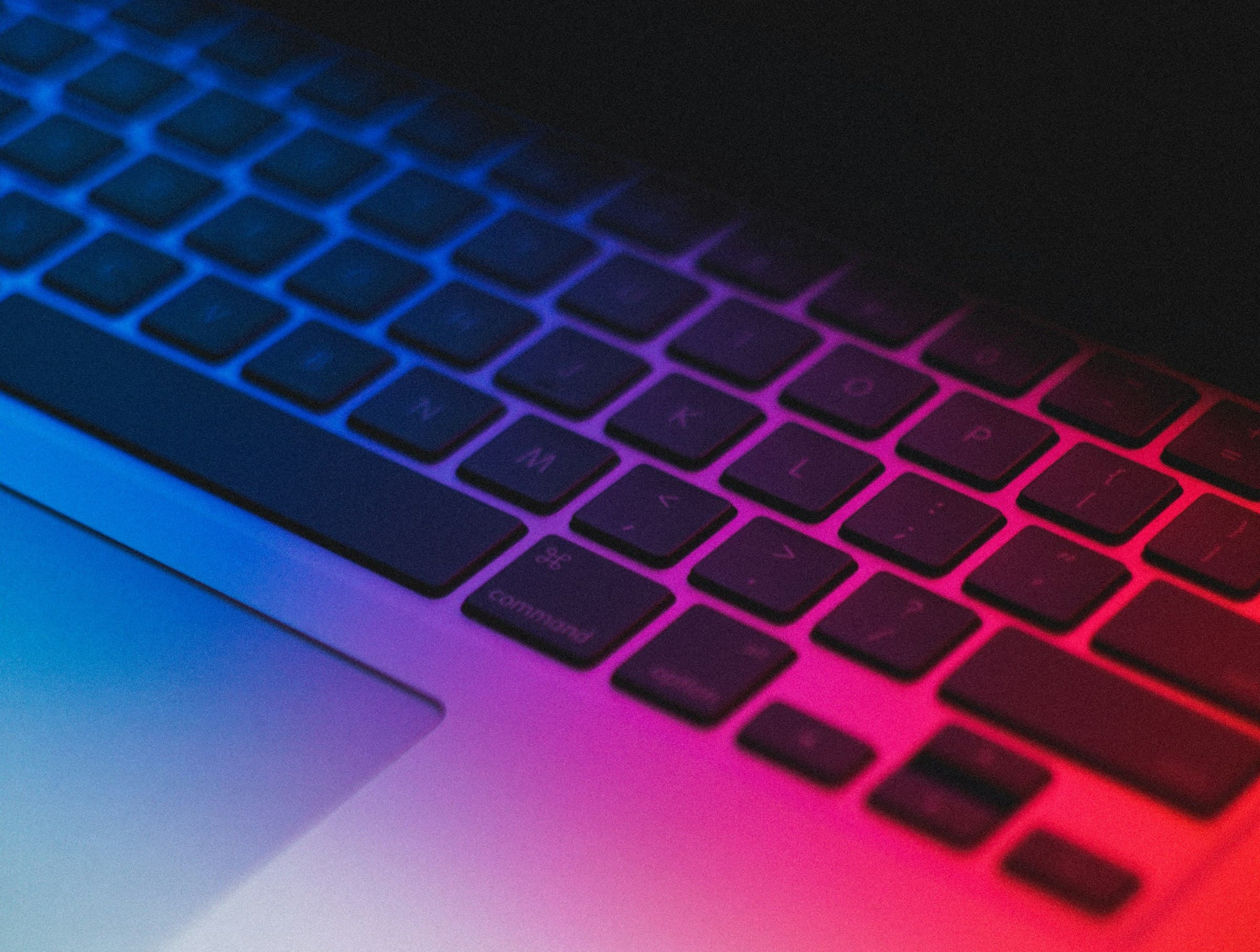 A Mac keyboard glowing with rainbow light
