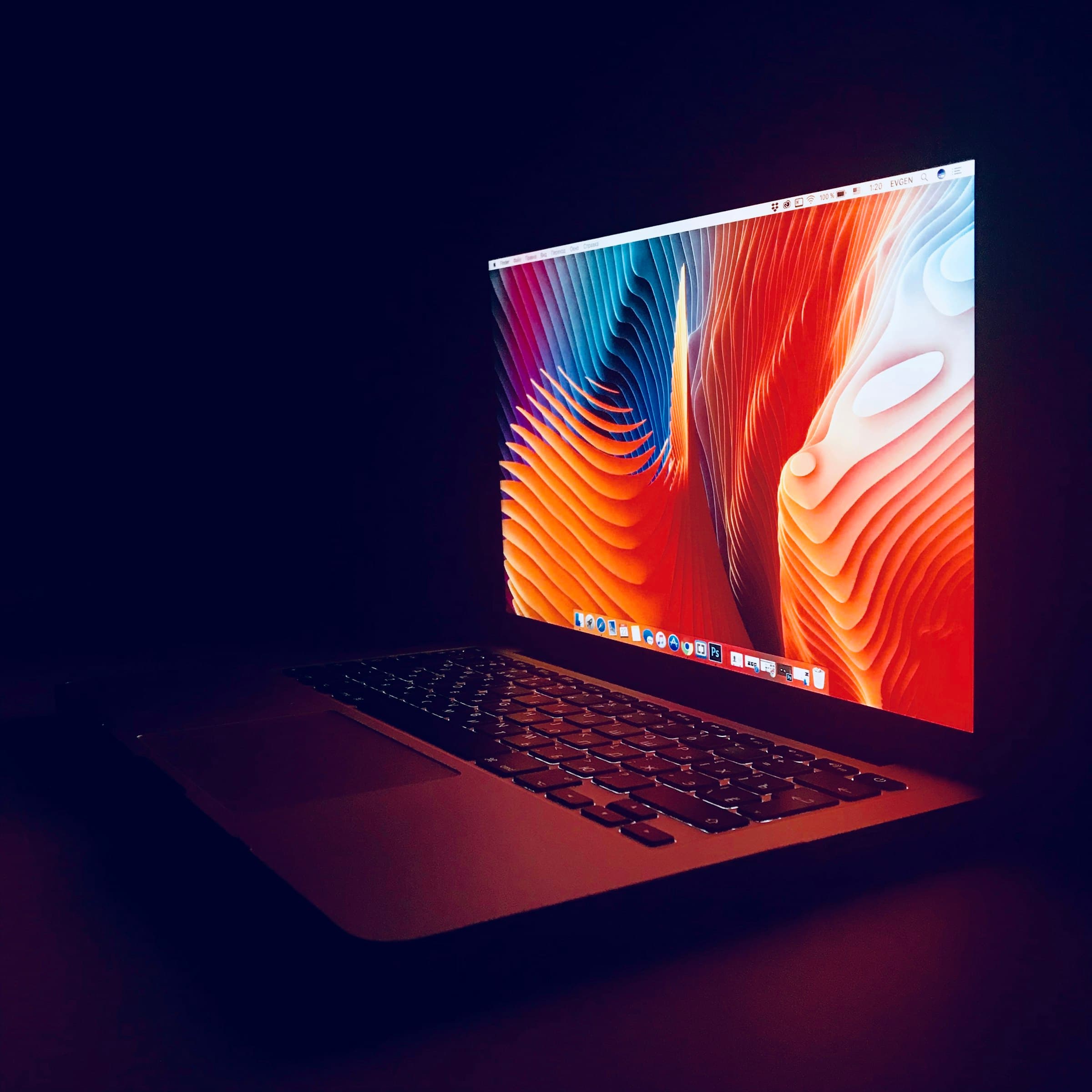 A closed MacBook on a desk in a darkened room